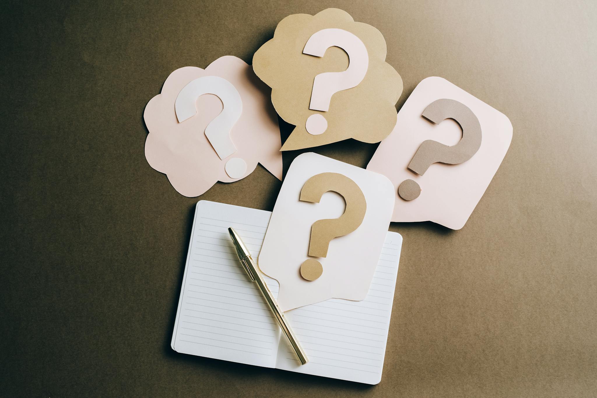 Flat lay of question mark paper crafts on a notebook, symbolizing questions and ideas. Contact graphiste freelance