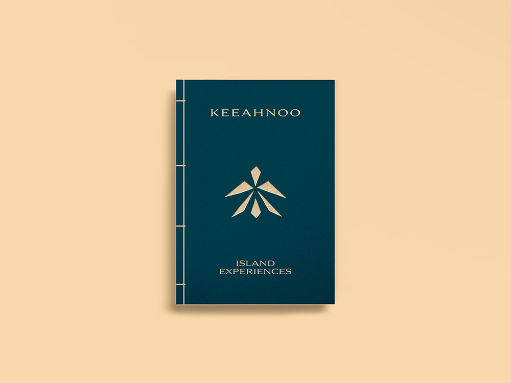 Couverture de la brochure de l'hôtel Keeahnoo en papier bleu avec marquage doré, posée sur fond jaune rosé